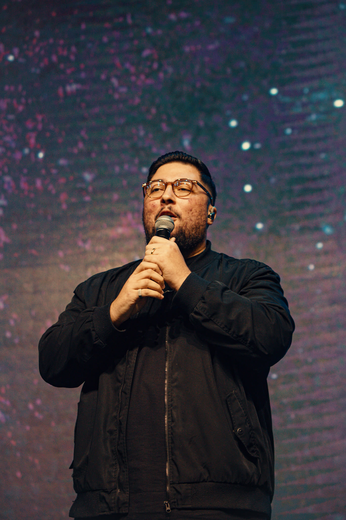 Cantor com microfone diante de um telão estrelado